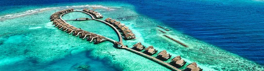 Aerial view of an overwater villa resort on a Maldives atoll